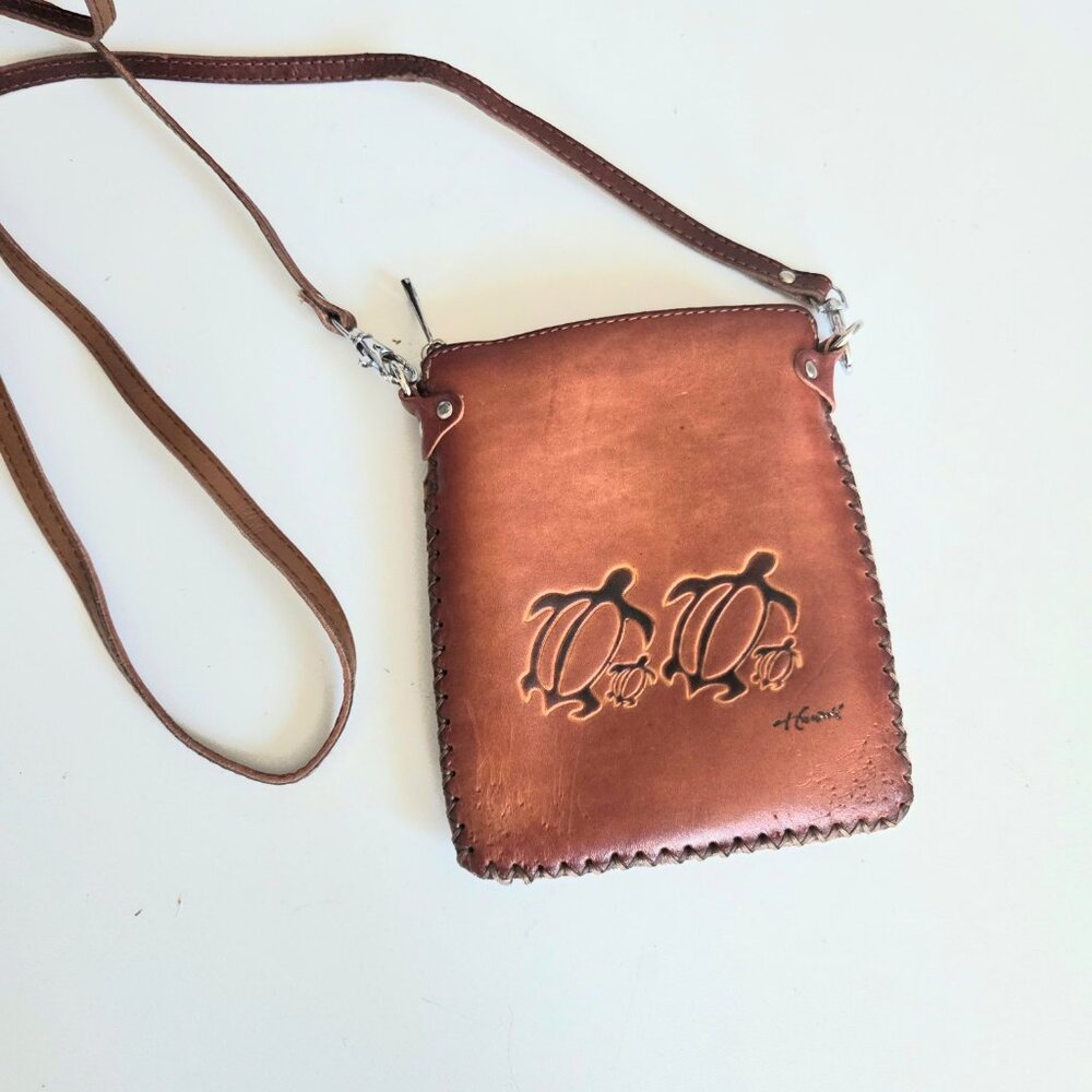 Small crossbody caramel brown leather bag with turtle design.